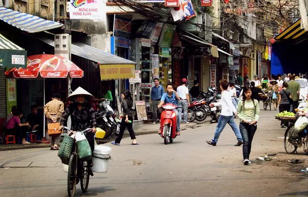 A busy Vietnamese street with motorbikes, shops and a woman wearing a conical hat